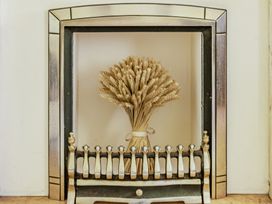 A fireplace with a wheat bouquet and fireplace fender at Tyn Y Ffynnon in Betws-Y-Coed