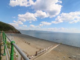 A beach with sand and pebbles and a metal railing along a path at Enfys in Criccieth