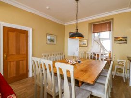 A dining room with a wooden table surrounded by chairs and a model sailboat on a side table at Enfys in Criccieth