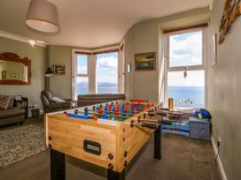 A living room with a foosball table and windows looking out to the sea at Enfys in Criccieth