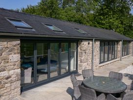 An outdoor area with a stone wall and glass doors at Limestone in Great Urswick