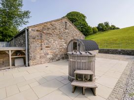 An outdoor area with a stone building and wooden hot tub at Limestone in Great Urswick