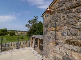 An outdoor shower next to a stone wall and shed at Limestone in Great Urswick