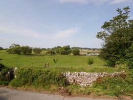 An outdoor view with grass, trees, and a stone wall at Limestone in Great Urswick