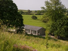 A view of a building surrounded by grass and trees at Limestone in Great Urswick