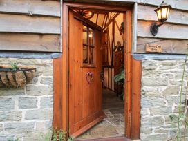 A wooden door open to show entrance hallway with stone floor and plants at Tawny Owl Barn in Leintwardine