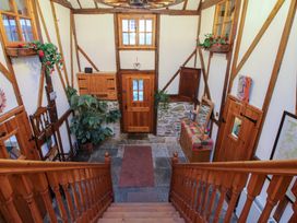 An entryway with a wooden door two rugs a wooden staircase plants and a wooden dresser at Tawny Owl Barn in Leintwardine