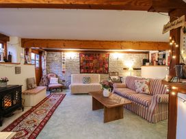 A living room with wooden beams stone walls striped sofa coffee table and a fireplace at Tawny Owl Barn in Leintwardine