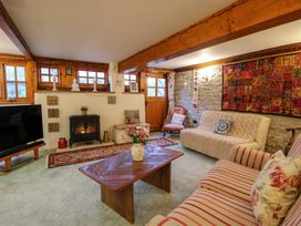 A living room with wooden beams a fireplace television sofas an armchair a wooden coffee table and a floral arrangement at Tawny Owl Barn in Leintwardine
