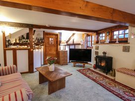 A living room with wooden beams a striped sofa a wooden coffee table a fireplace and a television at Tawny Owl Barn in Leintwardine