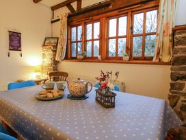 A dining table with a polka dot tablecloth teapot cups biscuits and flowers beside a window in a room with stone walls at Tawny Owl Barn in Leintwardine