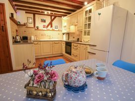 A kitchen with cream cabinets a white refrigerator a polka dot tablecloth with a floral teapot two mugs and flowers in glass vases at Tawny Owl Barn Leintwardine