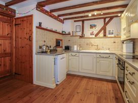 A kitchen with wooden floor and beams cream cabinets and tiled backsplash at Tawny Owl Barn in Leintwardine