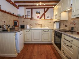 A kitchen with cream cabinets wooden floor a dishwasher oven microwave and a sink at Tawny Owl Barn in Leintwardine