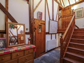 A wooden staircase and a wooden dresser with a mirror in a hallway with exposed wooden beams at Tawny Owl Barn in Leintwardine