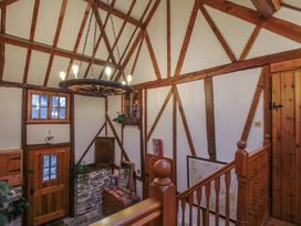 A hallway with wooden beams stone walls a wooden door a staircase and a chandelier at Tawny Owl Barn in Leintwardine