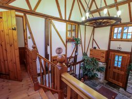 A wooden staircase with railing leading down to an entrance door with windows and plants at Tawny Owl Barn in Leintwardine