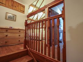 An upstairs landing with wooden railing and chest of drawers next to a bedroom and bathroom door at Tawny Owl Barn in Leintwardine