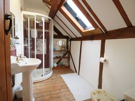 A bathroom with wooden floor beams skylight shower sink and toilet at Tawny Owl Barn in Leintwardine