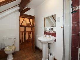 A bathroom with a toilet sink mirror and shower with wooden beams visible at Tawny Owl Barn in Leintwardine