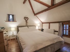 A bedroom with a double bed lamps on side tables and wooden beams at Tawny Owl Barn in Leintwardine