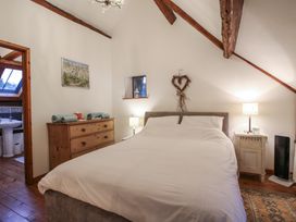 A bedroom with a double bed bedside tables lamps chest of drawers and exposed wooden beams at Tawny Owl Barn in Leintwardine