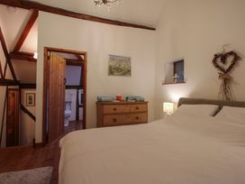 A bedroom with a bed a wooden dresser and an open door leading to a bathroom at Tawny Owl Barn in Leintwardine