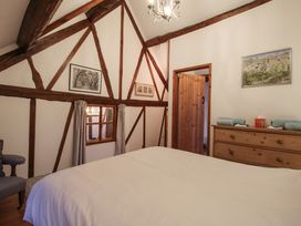 A bedroom with wooden beams a bed a dresser with towels and framed pictures on the walls at Tawny Owl Barn in Leintwardine