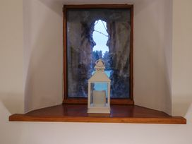 A window with a wooden sill holding a white lantern with a candle inside