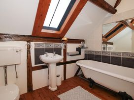 A bathroom with a toilet sink and clawfoot bathtub under a skylight at Tawny Owl Barn in Leintwardine