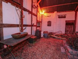 A rustic indoor area with wooden beams sticks a wooden table a barrel and white walls at Tawny Owl Barn in Leintwardine