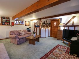 A living room with a striped sofa, wooden coffee table, bookshelf, wooden beams, and a TV at Tawny Owl Barn in Leintwardine
