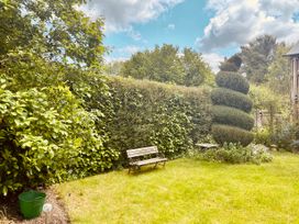 A garden with a wooden bench lawn a spiral shaped topiary and dense hedges at Tawny Owl Barn in Leintwardine