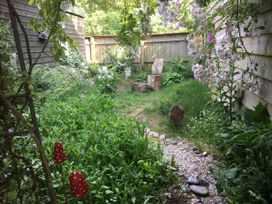 A small garden with wooden fences plants flowers and a wooden chair at Tawny Owl Barn in Leintwardine