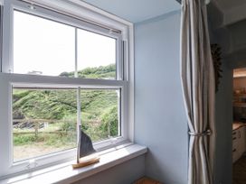 A window with a countryside view and a decorative sailboat at 2 Cliff Cottages West Portholland near Gorran Haven