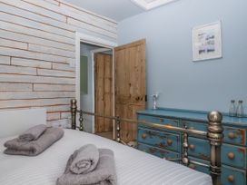 A bedroom with a bed and towels folded at 2 Cliff Cottages near West Portholland