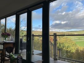 A dining area with flowers on a table and an outdoor view at The Sett on the Wharfe in Skipton
