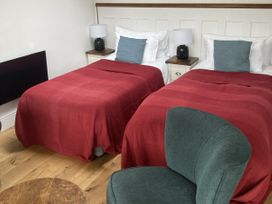 A bedroom with two beds and a chair at The Sett on the Wharfe Skipton