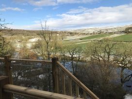 A view of a river and fields from a wooden railing at The Sett on the Wharfe Skipton