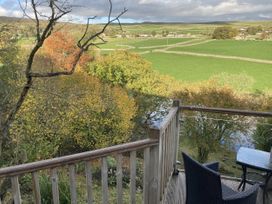 A balcony with a table and chair overlooking a landscape at The Sett on the Wharfe in Skipton