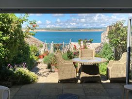 A garden with a table and chairs overlooking the sea at Mariners Cottage in Appledore