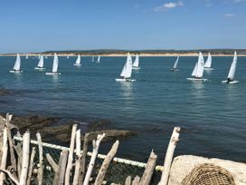 A view of sailboats on water near rocks and a fence at Mariners Cottage in Appledore
