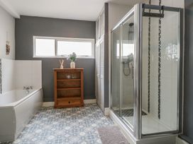 A bathroom featuring a bathtub, shower, and wooden shelf at 4 Trafalgar Square, Great Yarmouth