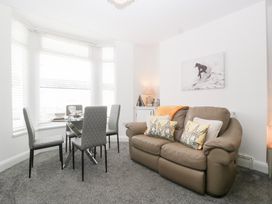 A living room with a sofa and dining table at 76A Mackworth Road in Porthcawl