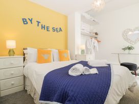 A bedroom with a blue quilt and yellow wall at 76A Mackworth Road Porthcawl