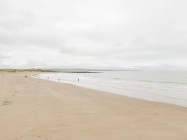 A beach with people walking along the shore at 76A Mackworth Road Porthcawl