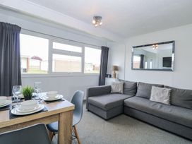 A living room with a grey sofa dining table set with plates glasses and a plant large wall mirror at California Summers in California Norfolk