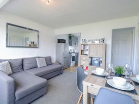 A living room with a grey sofa a dining table set with white dishes and a wooden cabinet with the word home on top at California Summers California Norfolk
