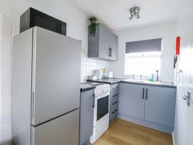 A kitchen with grey cabinets a stove a refrigerator and a window at California Summers in California Norfolk