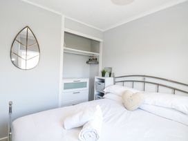 A bedroom with a metal bed frame white bedding rolled towels a heart shaped cushion a small shelf with plants an open closet and a leaf shaped mirror on the wall at California Summers in California Norfolk